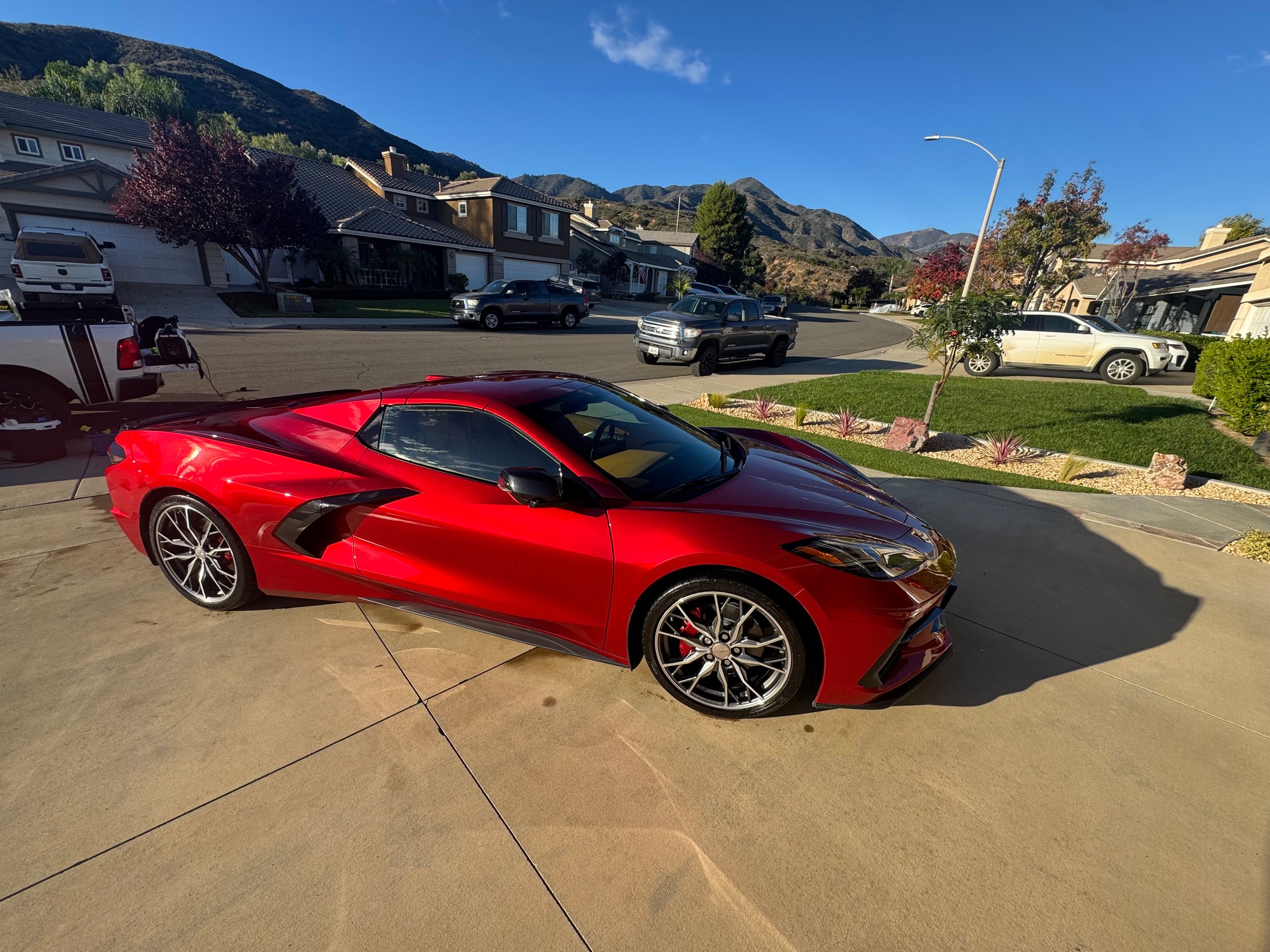 Bright red sports car parked in suburban driveway with mountains in background