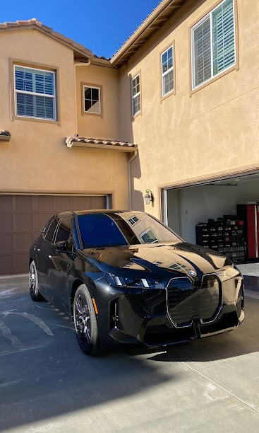 Black BMW SUV parked in front of tan suburban home with open garage