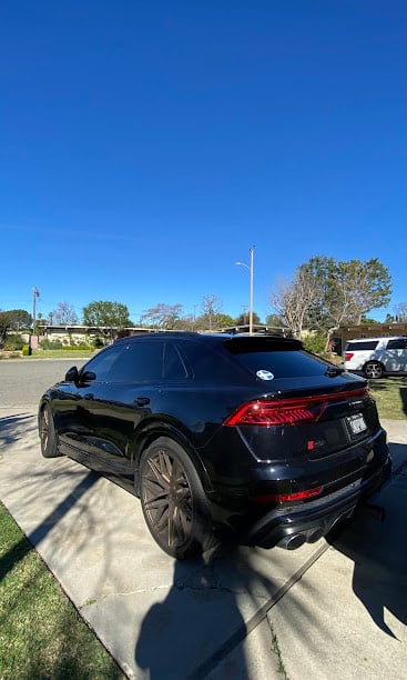 Black luxury SUV parked on street with blue sky background